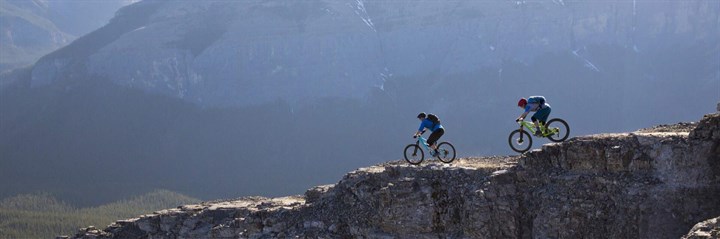 Two cyclists on a ridgeline in the mountains
